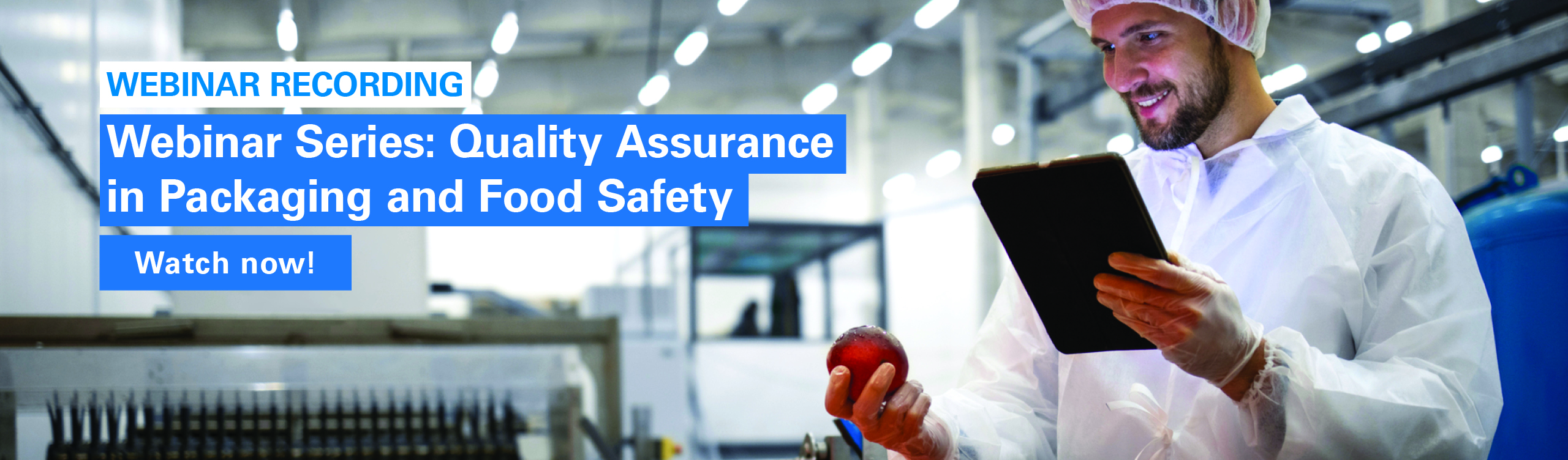 Picture shows a food inspector in an industrial surrounding who is holding a clipboard and is looking at a fruit.