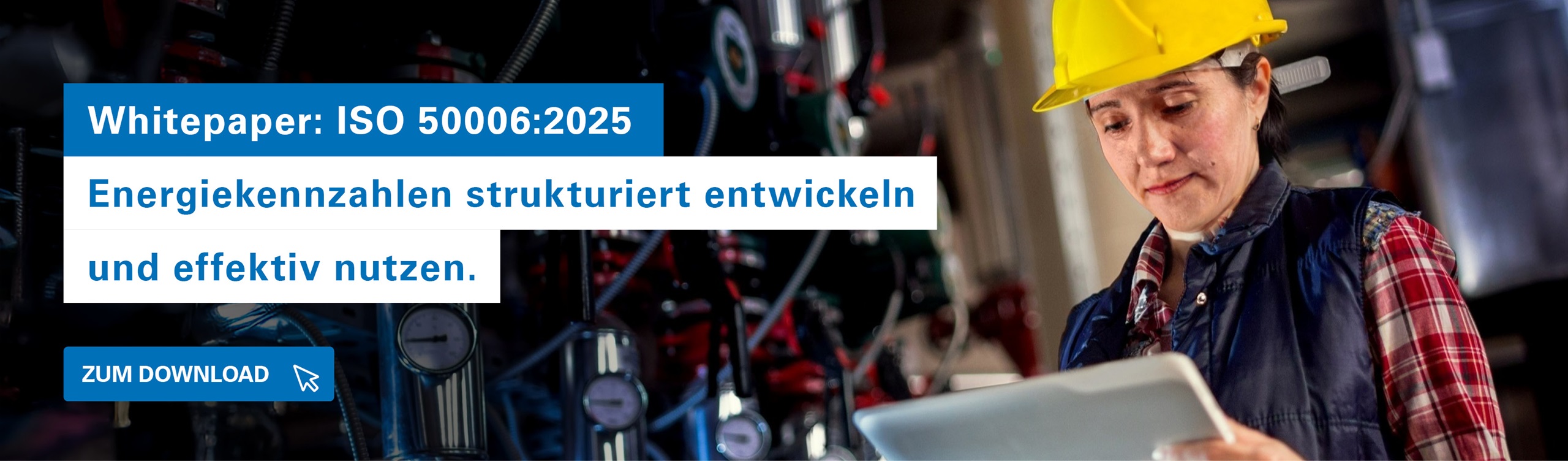 Person mit gelbem Schutzhelm prüft Energiekennzahlen mit einem Tablet in einer Industrieanlage mit Maschinen im Hintergrund.