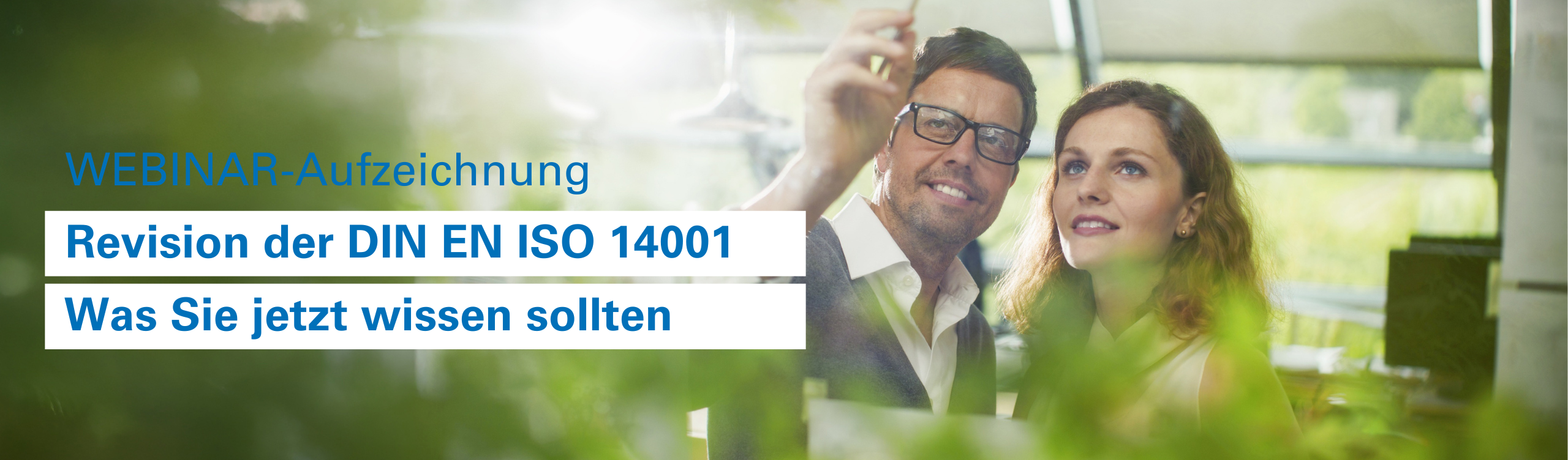 Zwei Personen in einem fachlichen Austausch zu Umweltmanagement in einem lichtdurfluteten Büro mit einer Reihe von Grünpflanzen.